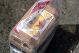 A cardboard box bearing a sticker showing a yellow smiley face and two thumbs-up hands, wrapped in plastic.