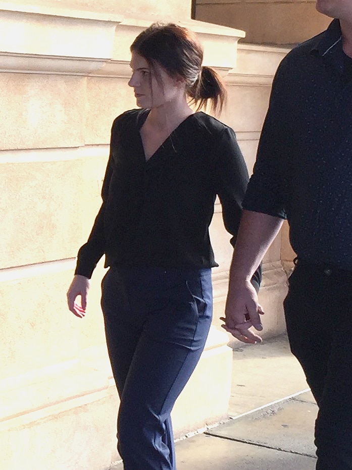 A man and woman hold hands outside court.