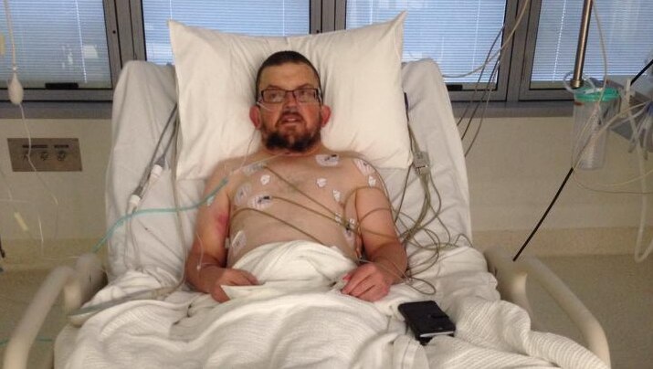 Bruce McCardel lies in a hospital bed. He is hooked up to monitors and machines