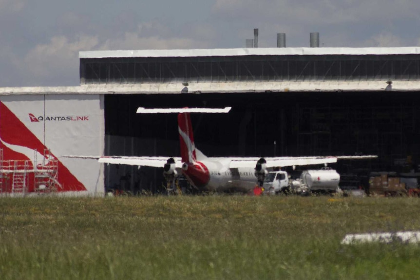 View across the tarmac to a huge workshop hanger with Qantas logos, and a plane parked in front