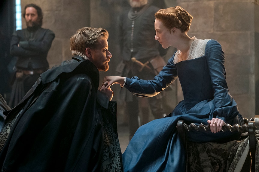 Colour still of Jack Lowden kissing the hand of Saoirse Ronan in 2018 film Mary Queen of Scots.