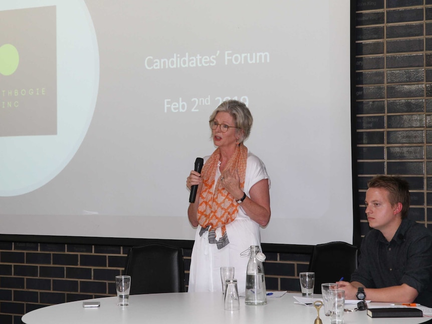 Helen Haines speaks into microphone in front of sign reading 'Candidates Forum'