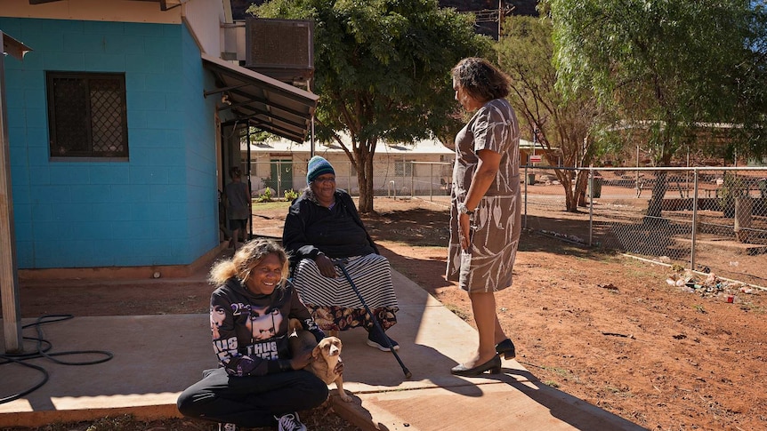 Leanne Liddle talks to three women outside community housing in Areyonga.