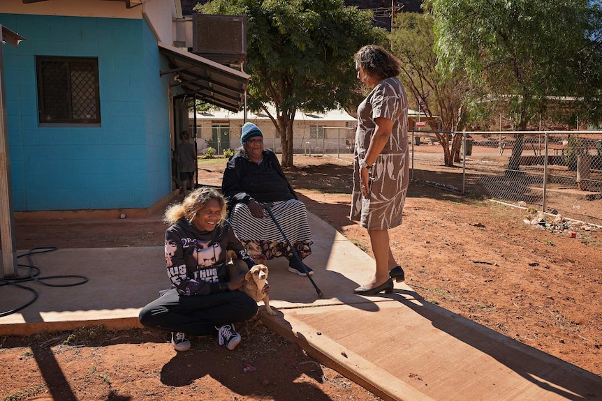 Leanne Liddle talks to three women outside community housing in Areyonga.