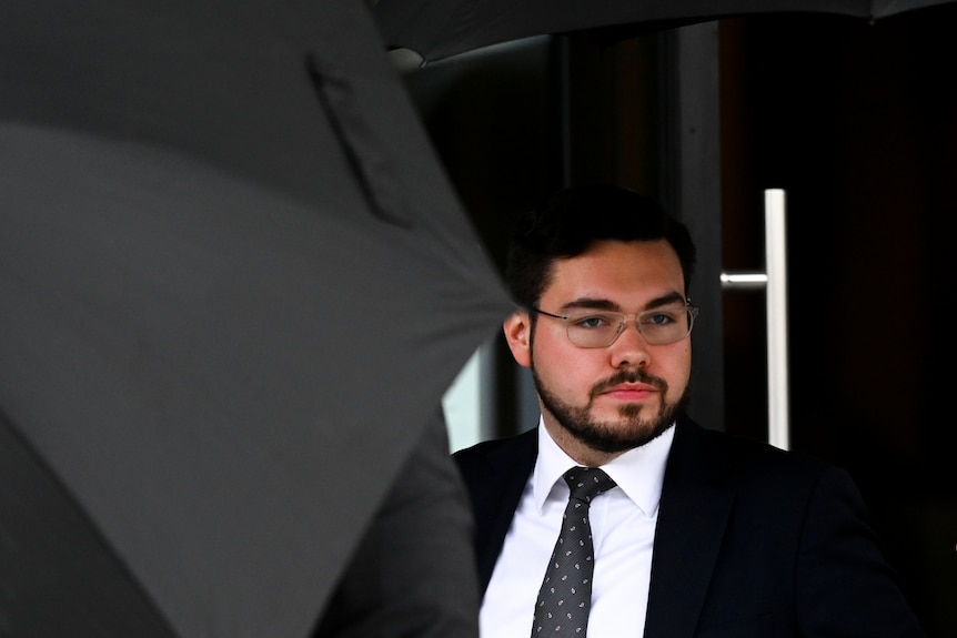 Bruce Lehrmann walks with an umbrella outside court.