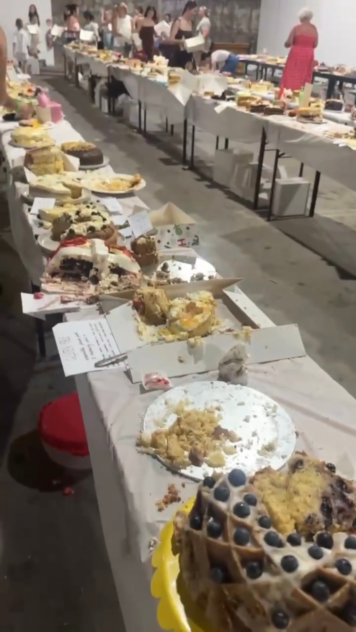 Una foto de muchos pasteles a medio comer en una mesa larga