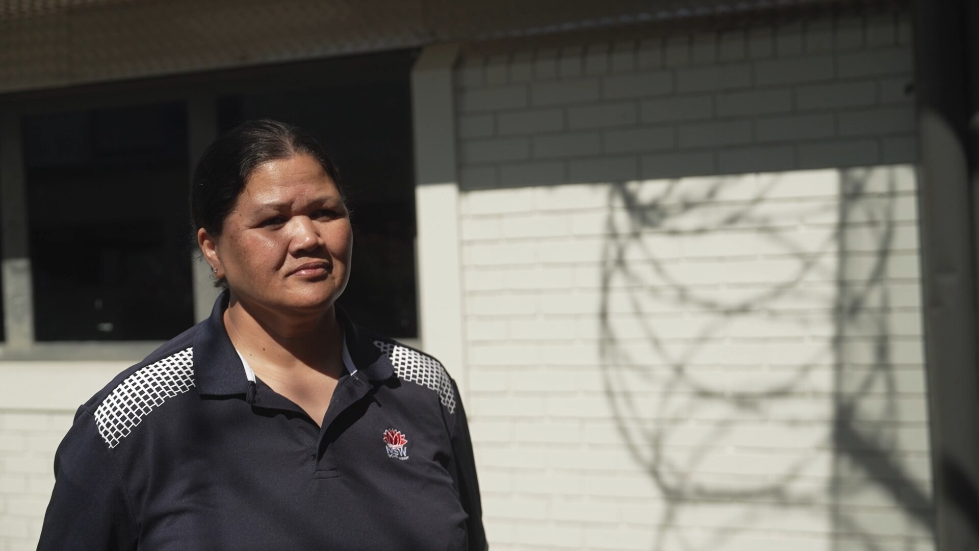 A woman stand sin front of a wall at a Youth Justice Centre.