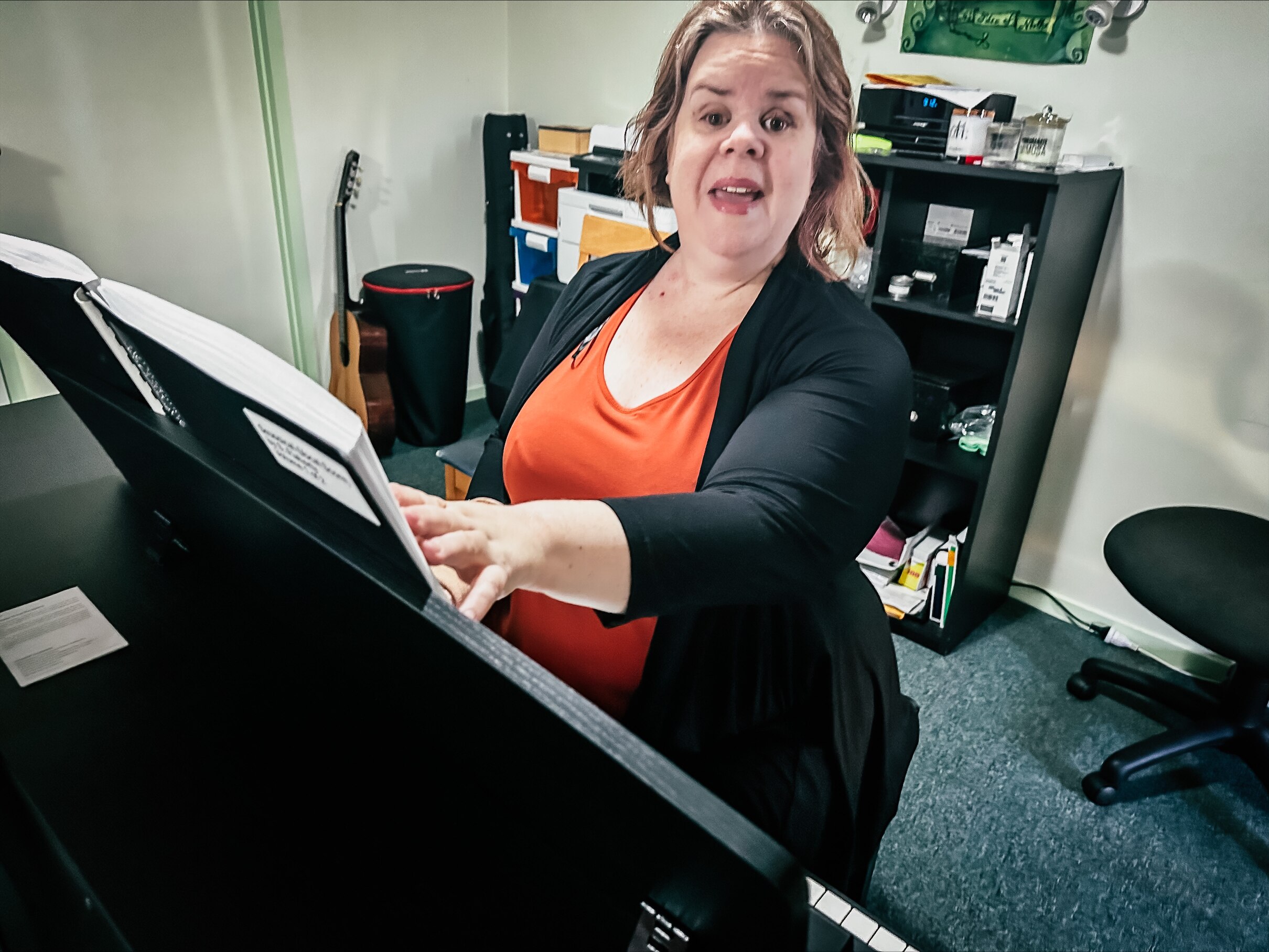 Julee-anne Bell sits at a piano reading Braille sheet music