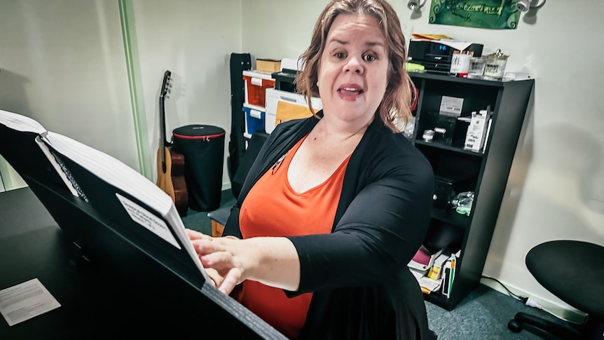 Julee-anne Bell sits at a piano reading Braille sheet music