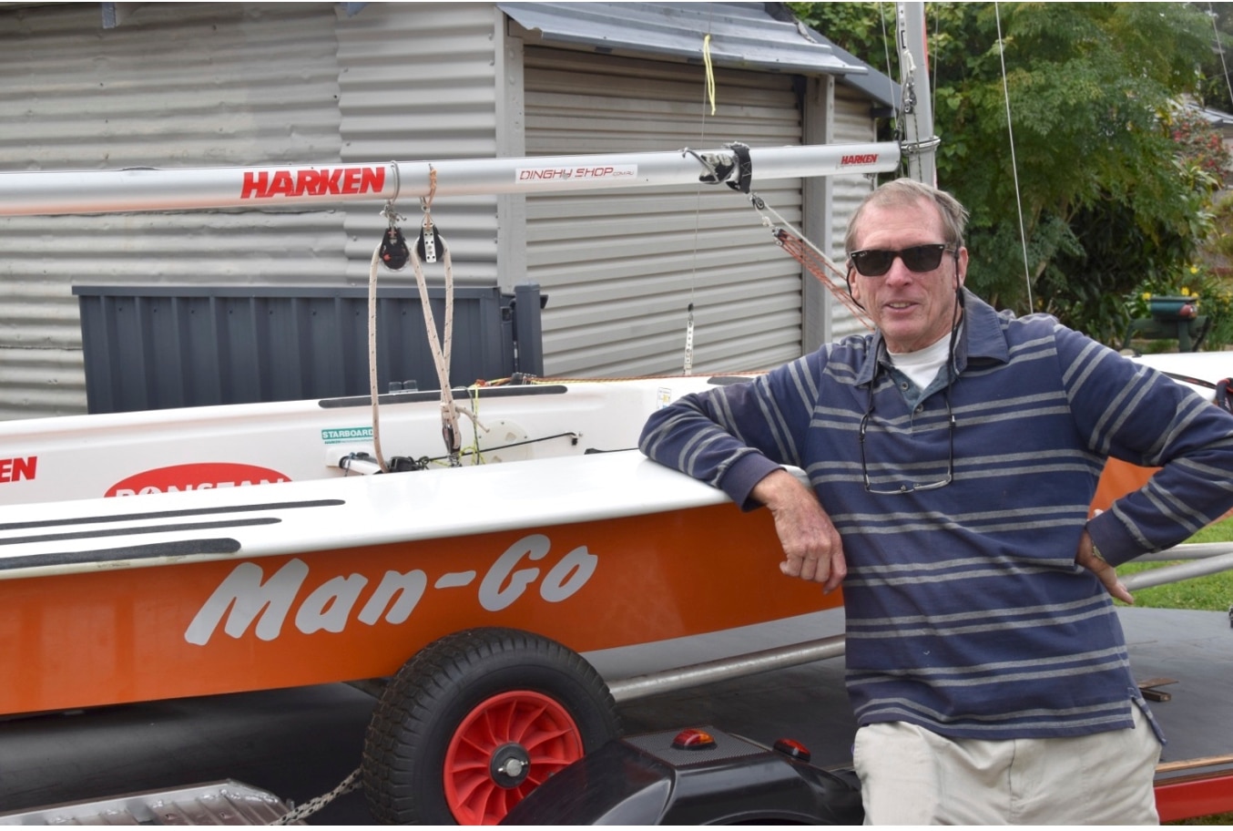 a man wearing a striped long-sleeve polo next to a boat.