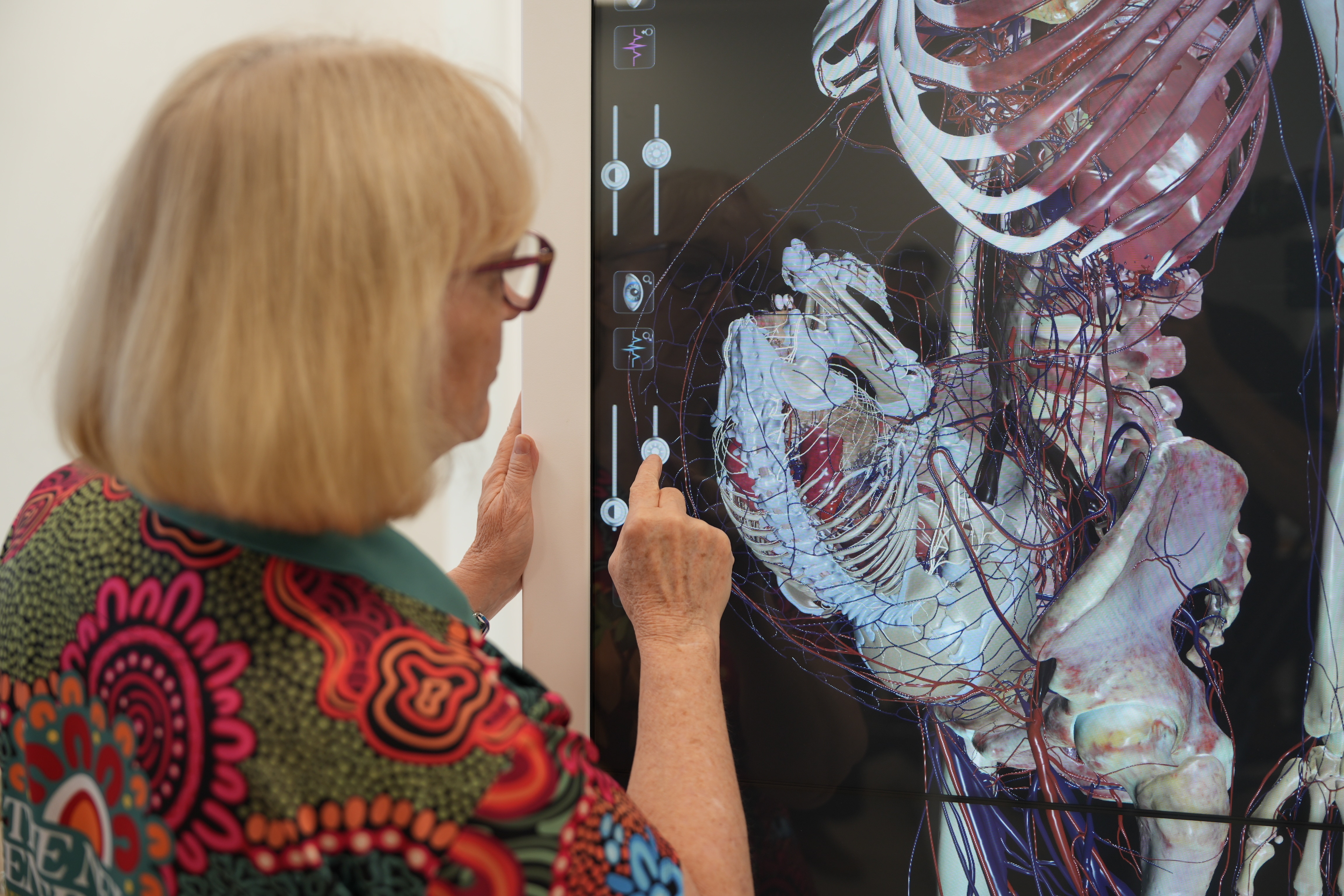 A woman touching a button on a screen, which shows the anatomy of a pregnant woman.