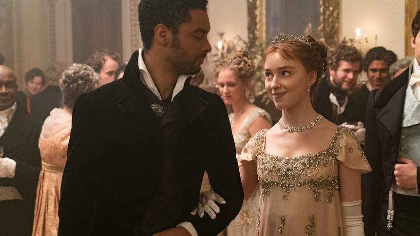 A black man and white woman looking at each other arm in arm, dressed in period costume