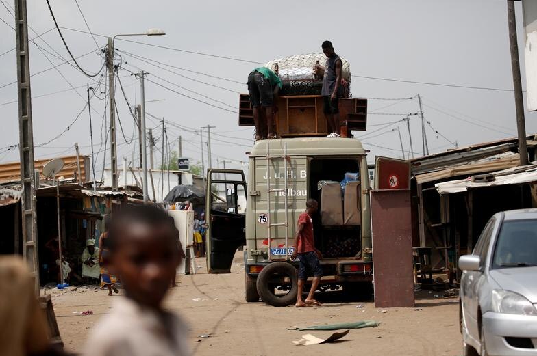 People packing a truck with cupboards and coaches in a township in Ivory Coast.