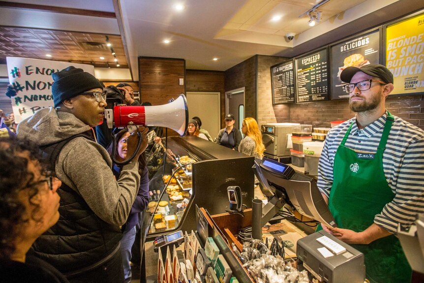 Black Lives Matter activist Asa Khalif yells at a Starbucks employee with a megaphone.