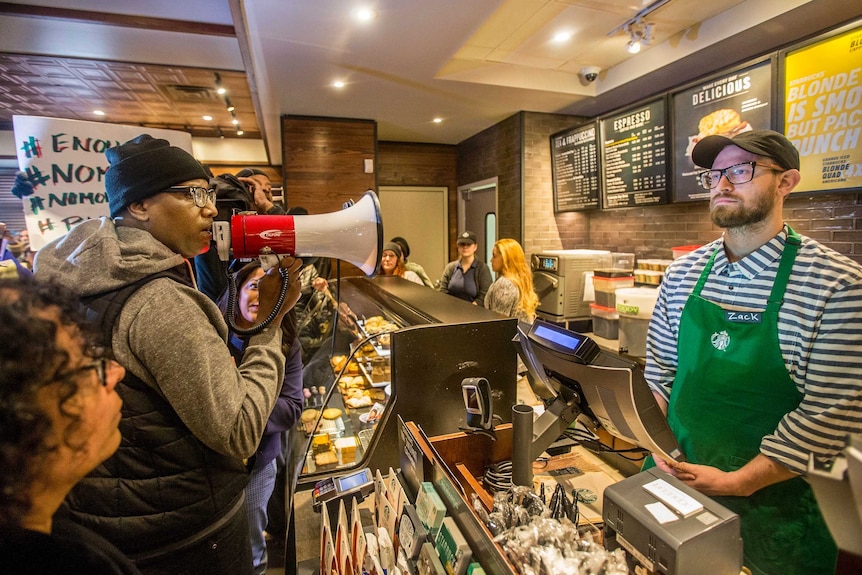 Black Lives Matter activist Asa Khalif yells at a Starbucks employee with a megaphone.