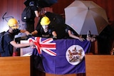Protesters put a Hong Kong colonial flag and deface the Hong Kong logo at the Legislative Chamber.