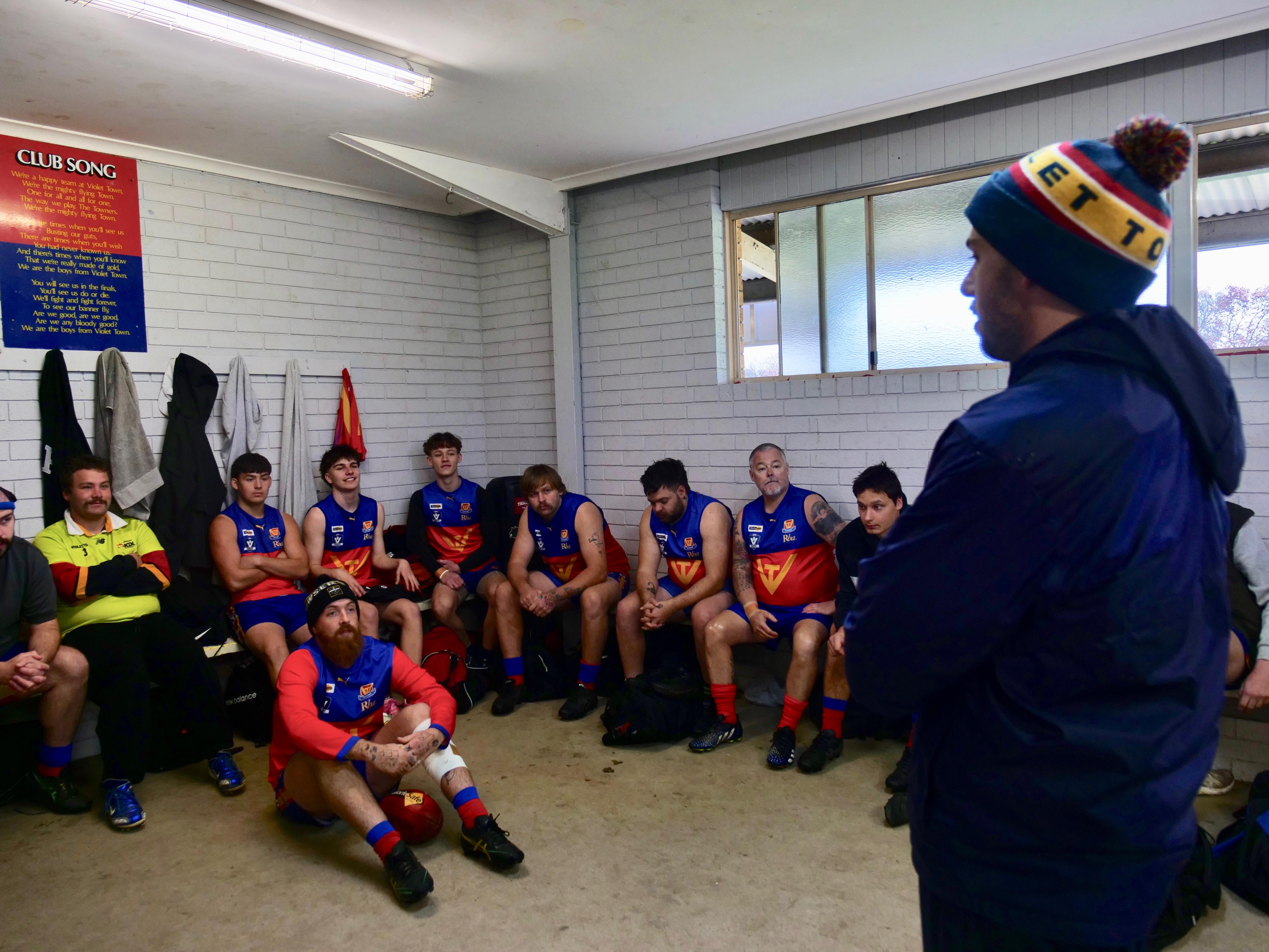 Coach speaking to his team in the rooms before a footy match