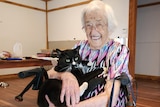 An elderly woman holding a black cat and smiling