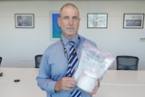 A police officer with a bag that holds a container filled with a white crystal substance