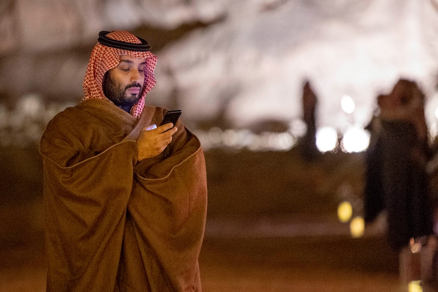Saudi sheik looks down at his phone screen 