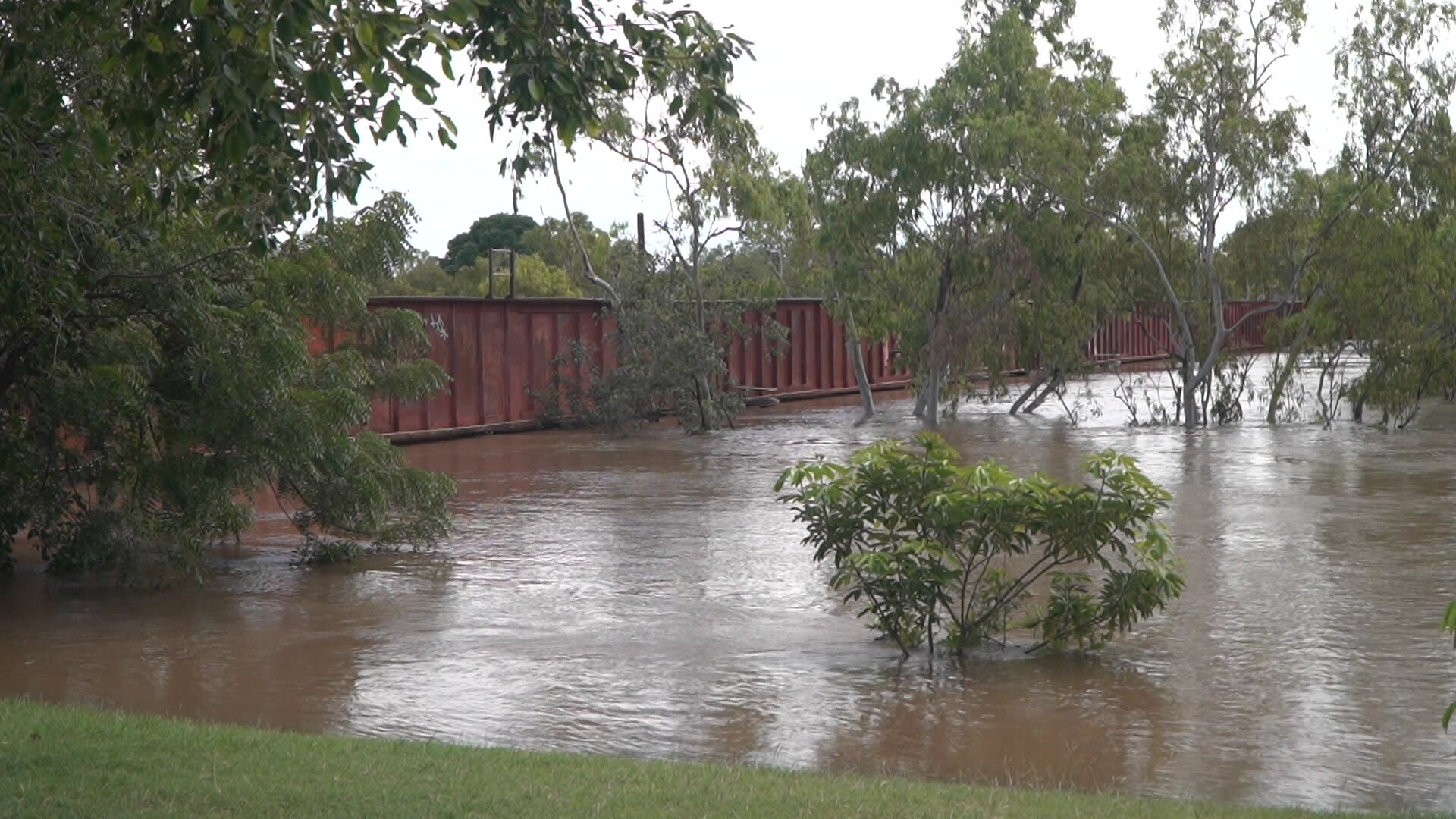 A flooded waterway coming up to the underside of a bridge.
