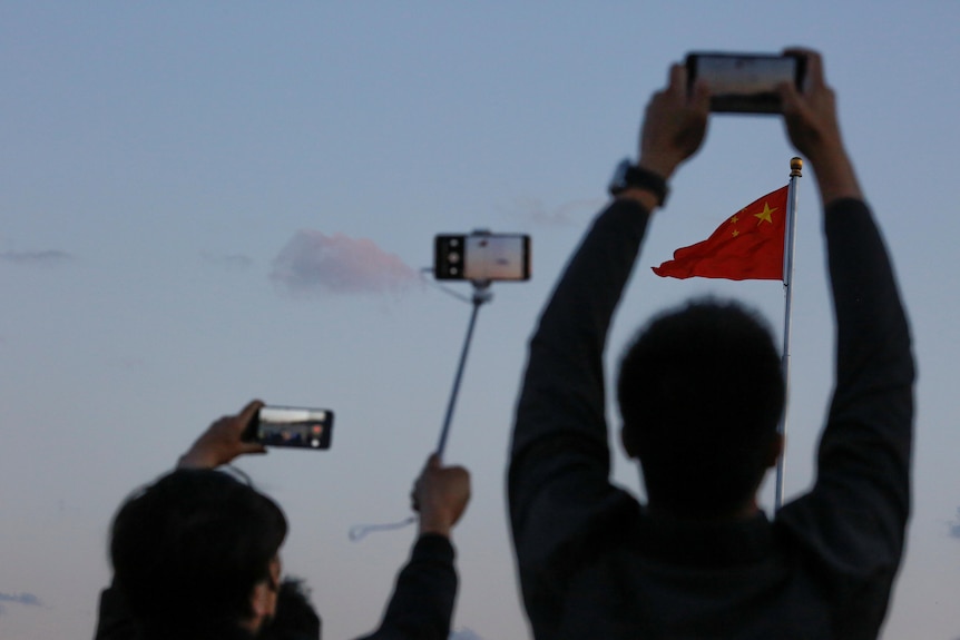 一个人正拿着手机对中国国旗拍照