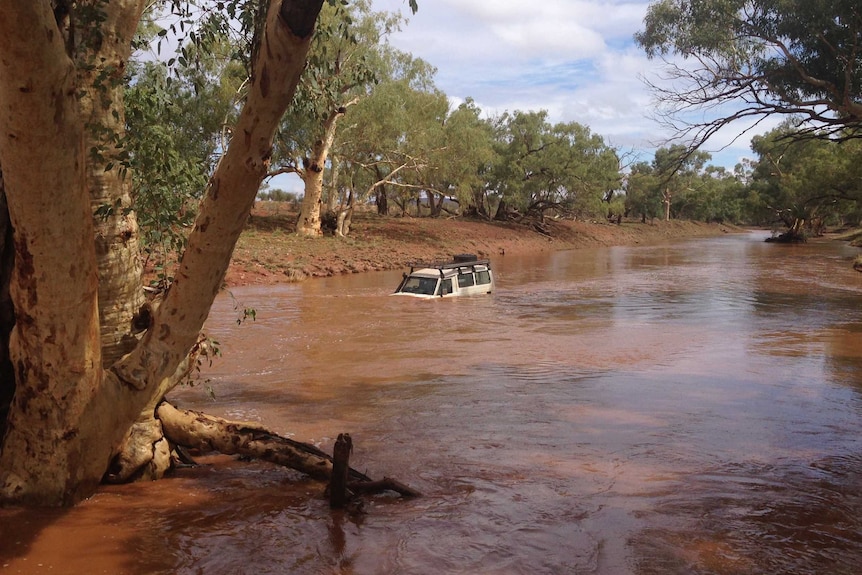 A four-wheel-drive which was washed away after the driver attempted to cross a flooded road near Santa Teresa, NT.