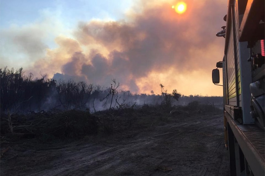 Smoke blocks the sun as a bushfire burns in a paddock