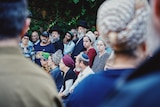 A large crowd of sad people, seen from behind two people standing