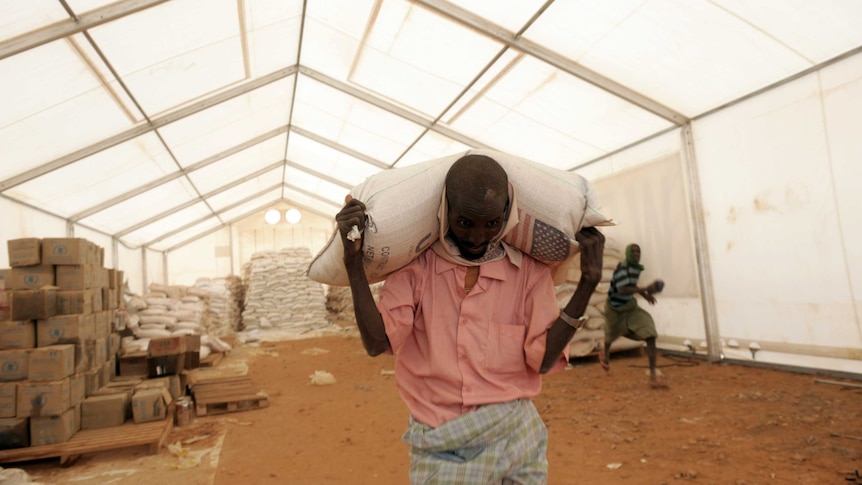 A relief worker carries a bag of food aid in Ethiopia.