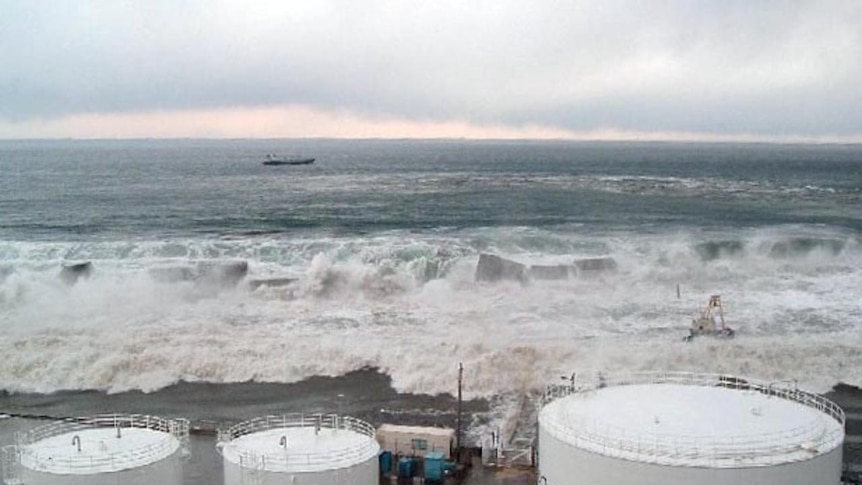 The tsunami surges over a sea wall and heads for the power station