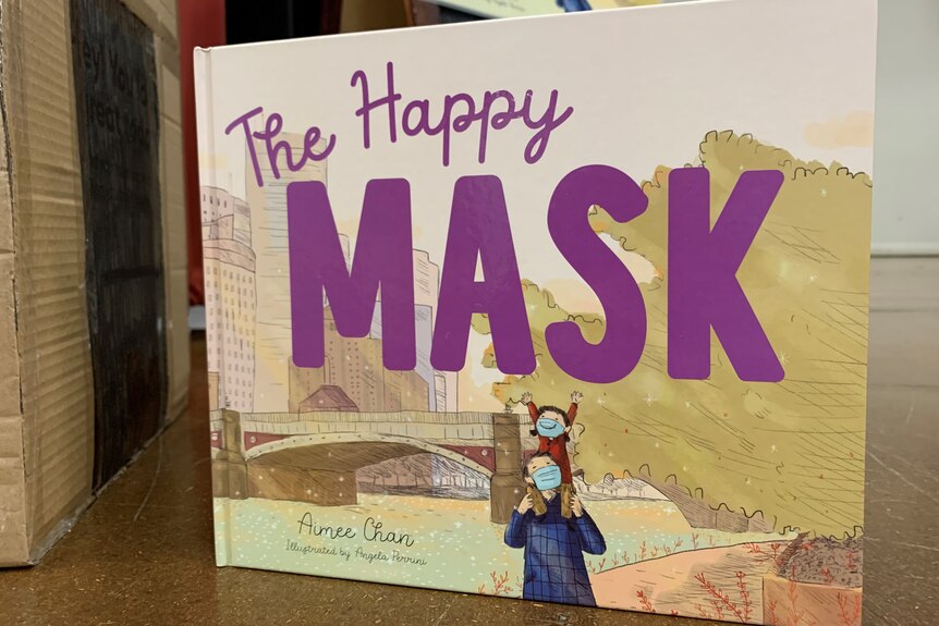 Book cover of The Happy Mask shows sketch of father giving his daughter a shoulder ride, both wearing masks.