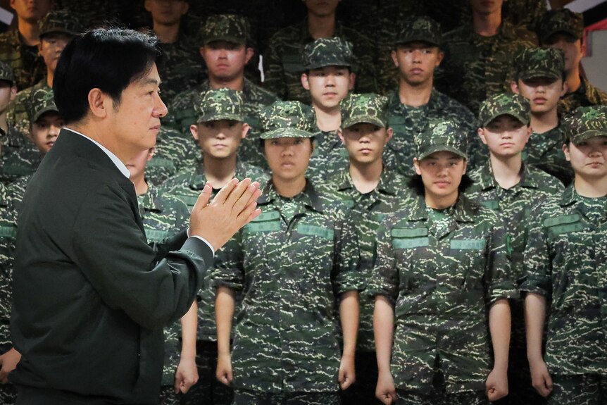 Lai Ching-te claps while walking infront of a group of soldiers.