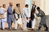 An Afghan policeman searches voters