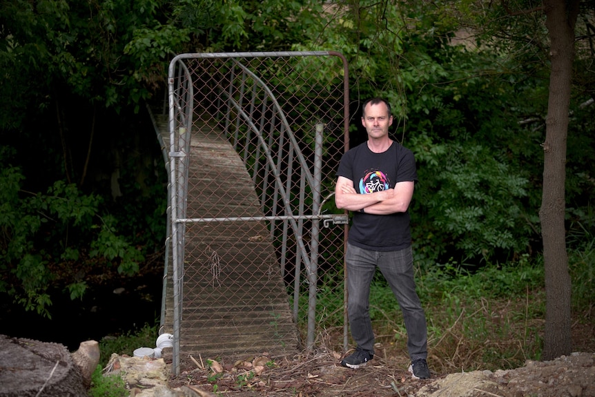 A man standing outside a bridge with a gate to it
