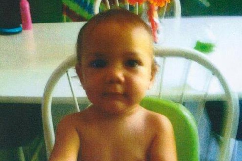 A head and shoulders shot of a shirtless baby boy sitting in a high chair.