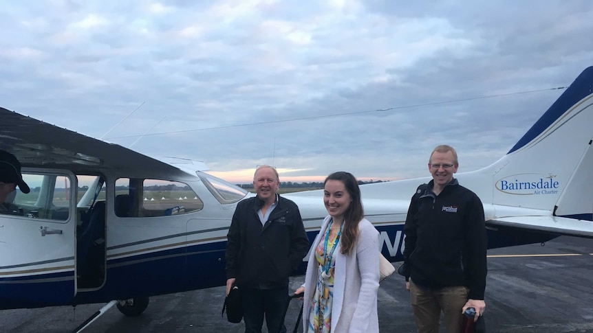 Three staff from the Bairnsdale area health service standing in front of the light aircraft that flies them to Mallacoota.