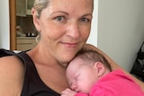 A new mum smiles while her newborn daughter sleeps on her chest