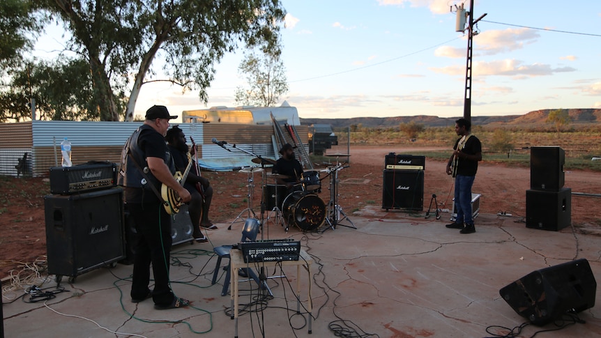A group of men rehearsing for their performance while the sun sets in central australia.