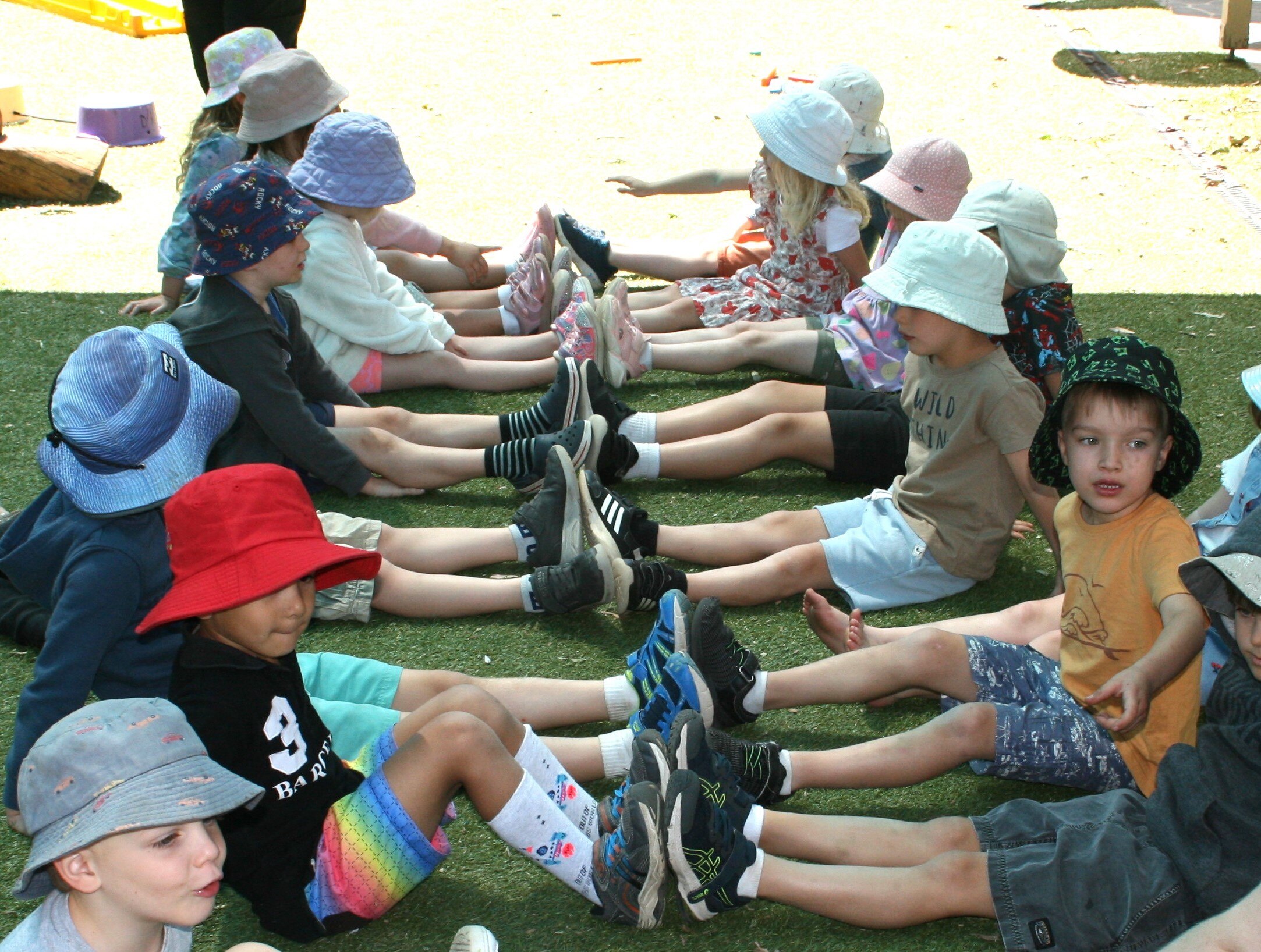 Preschoolers sit opposite their partner, ready for the team game Fruit Salad. 