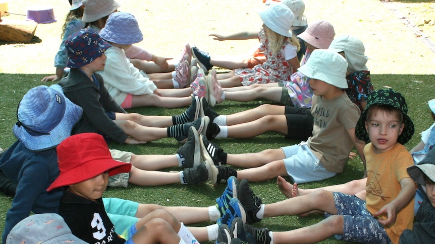 Preschoolers sit opposite their partner, ready for the team game Fruit Salad. 