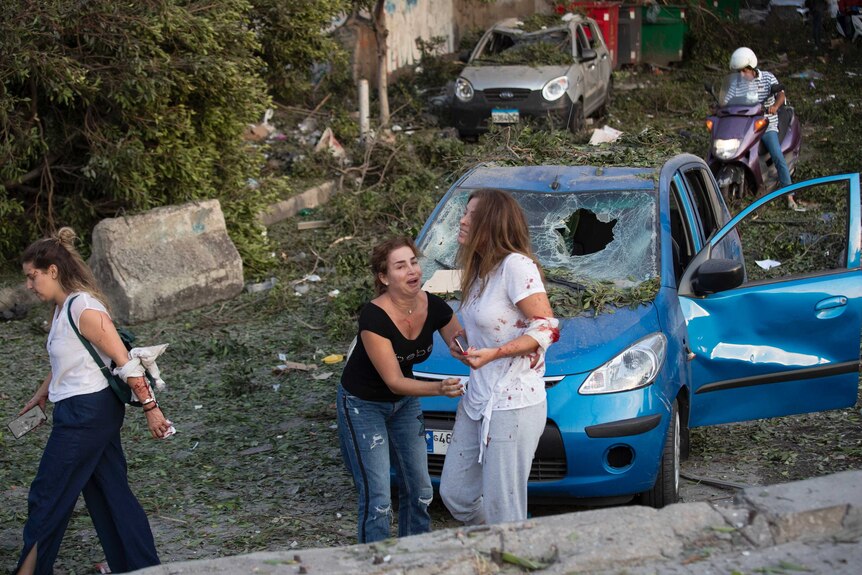 Two women appear to have superficial wounds amidst smashed cars.