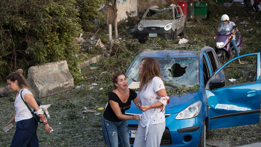 Two women appear to have superficial wounds amidst smashed cars.