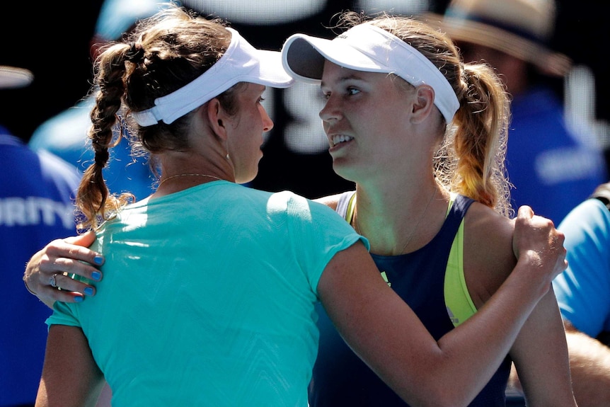 Caroline Wozniacki and Elise Mertens embrace at the net at the Australian Open.