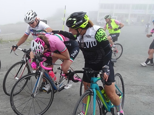 A woman on her bike is bent over her handlebars, overcome with emotions.