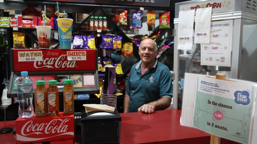 A man stands behind the lolly counter of a regional cinema