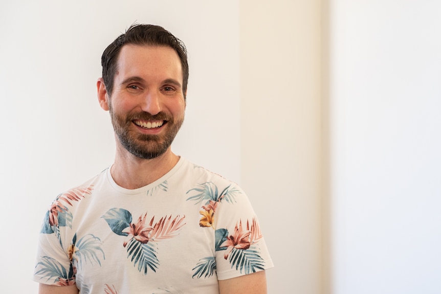 Man in floral t-shirt smiling, white background