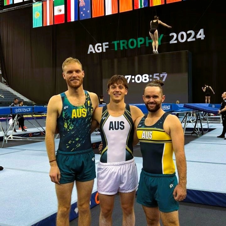 Three male gymnasts at a competition in their Australian outfits.