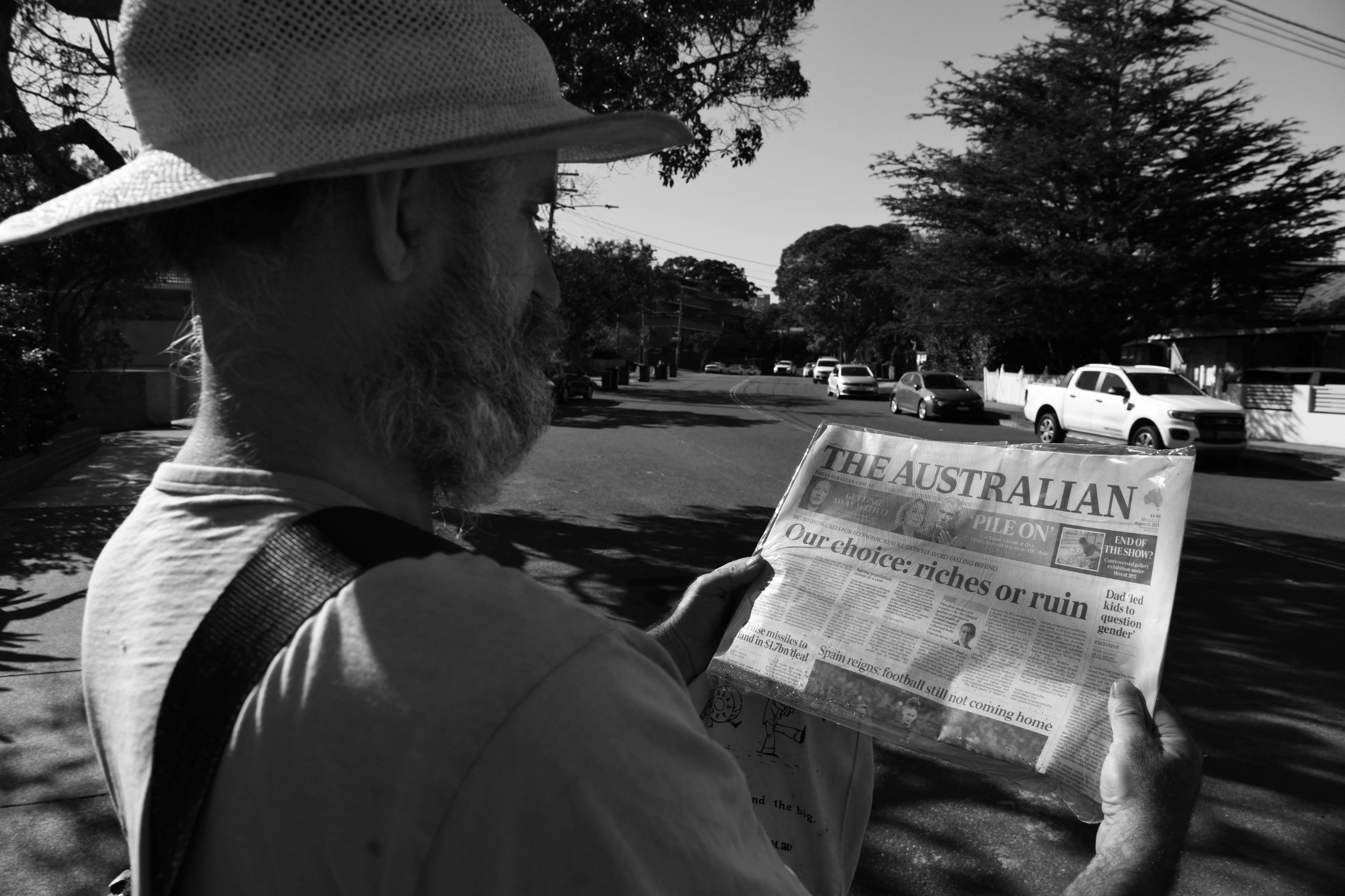 A man looks at a copy of a newspaper with the words 'our choice: riches or ruin'