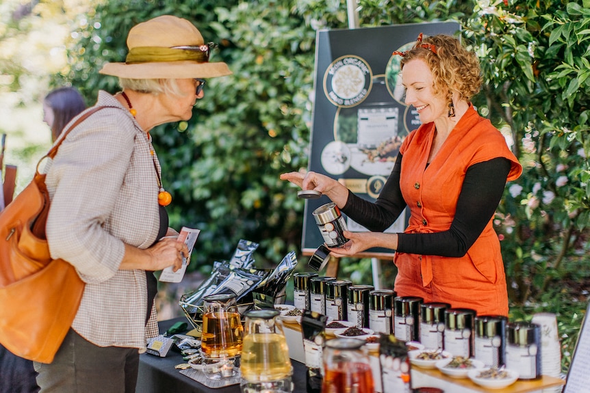 Belinda Hellyer at a market tea stall with a customer. 